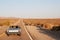 Couple driving convertible car on desert highway, back view