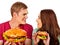 Couple eating fast food. Man and woman eat hamburger with ham.