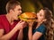 Couple eating fast food. Man and woman treat hamburger .