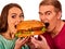 Couple eating fast food. Man and woman treat hamburger .
