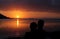 Couple embraced in front of a beautiful sunset by the sea