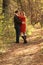 Couple embracing on trail in fall wooded area as woman coyly smiles at camera