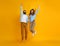 Couple of emotional people man and woman jumping on yellow background