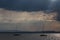 A couple of empty, little sailboat on a lake, beneath a moody sky with sun rays filtering through