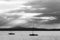 A couple of empty, little sailboat on a lake, beneath a moody sky with sun rays filtering through.