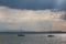 A couple of empty, little sailboat on a lake, beneath a moody sky with sun rays filtering through