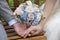 A couple in engagement and wedding holding each other`s hands with a bouquet of hand flowers in between