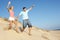 Couple Enjoying Beach Holiday Running Down Dune