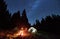 Couple enjoying starry night sky near campfire.