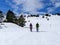 couple of excursionists walking on snowshoes and stick poles on the white snow of the winter of a path of a snowy mountain