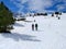 couple of excursionists walking on snowshoes and stick poles on the white snow of the winter of a path of a snowy mountain