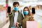 Couple In Face Masks Showing Phones Screens Shopping In Hypermarket