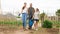 Couple of farmers with daughter carrying baskets with vegetables