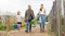 Couple of farmers with daughter carrying baskets with vegetables