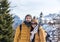 Couple in front of mountaintop village of Monte Lussari in Julian alps, Italy