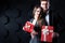 Couple with gifts. Beautiful man and woman holding gift boxes on a dark background