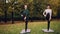 Couple of girls are doing yoga in park practising balancing exercises standing on one leg during individual yoga