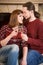 Couple with glass of champagne embracing together near fireplace