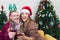 Couple with glasses of red wine near fireplace, Beautiful caucasian young woman in sweater and with santa hat on head sitting on