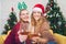 Couple with glasses of red wine near fireplace, Beautiful caucasian young woman in sweater and with santa hat on head sitting on