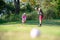 Couple golf player putting golf ball on the green golf.  Asia man and woman putting golf ball on tee with club in golf cour