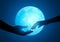 Couple hands reaching to one another on a full moon background