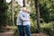 Couple of happy and cheerful people caucasian senior hug with love and smile with defocused green forest in background - outdoor