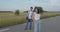 Couple of happy young teenagers stand in poses at camera on walk with skateboard