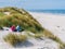 Couple having picnic on sand dune looking over beach and North Sea on West Frisian island Ameland, Friesland, Netherlands