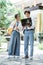 a couple of high school students stand holding books, wearing bags, and using a laptop computer