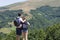 Couple of hikers with backpacks standing at viewpoint and enjoyi