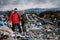 Couple of hikers walking across landfill, large pile of waste, environmental concept and eco activism.