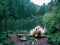 couple hikers in yellow raincoat looking at mountain lake