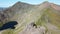 Couple hiking along a knife edge ridge up mount Snowdonia in Wales, UK