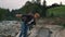 Couple hiking along mountain river. Travelers walking on rocky shore of river