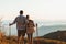 Couple hiking in autumn mountains with trekking sticks. View from behind