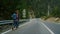 Couple hitchhikers walk mountains. Two travelers trekking on roadside highway.