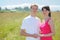 Couple hold hands, grass in field near village