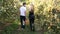 Couple holding basket full of apples walking through apple orchard