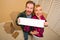 Couple Holding Blank Sign in Room with Boxes