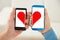 Couple holding cellphone with half heart symbol