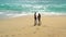 Couple holding hands on beautiful beach on holiday, aerial panning view