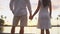 Couple holding hands in love enjoying vacation romantic at sunset at beach