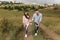 Couple holding hands are walking away. Portrait of a romantic young man and woman in love in nature