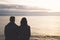 Couple hugging on the beach on background ocean sunrise, silhouette two romantic people cuddling and looking on rear view evening
