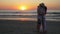 Couple hugging and kissing on the shore of sandy beach at sunset