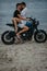 Couple hugs on beach sitting on motorcycle