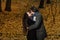 Couple hugs in a fall park. Golden Autumn on the background with leaves and trees, foliage.