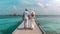 A couple on the jetty of a tropical beach in the Maldives during a vacation. Generative AI.