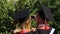 Couple of joyful graduates recording video on smartphone, graduation ceremony